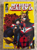 A copy of the My Hero Academia Volume 1 manga book by Kohei Horikoshi, featuring a bright yellow cover with illustrations of Aizawa and Deku.